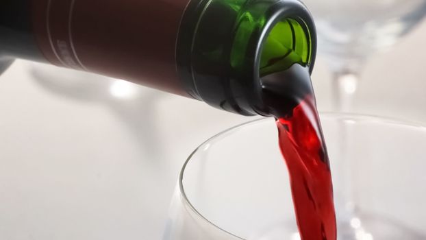 Red wine being poured from a bottle to a glass.