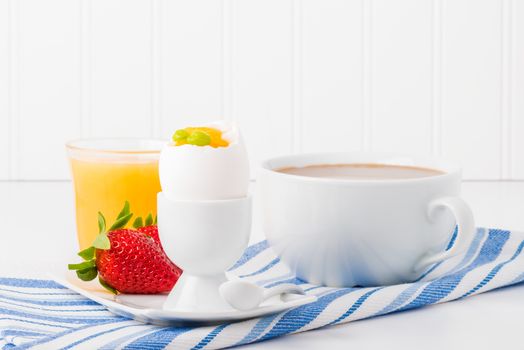 Soft boiled egg served with fresh fuit, coffee and orange juice.