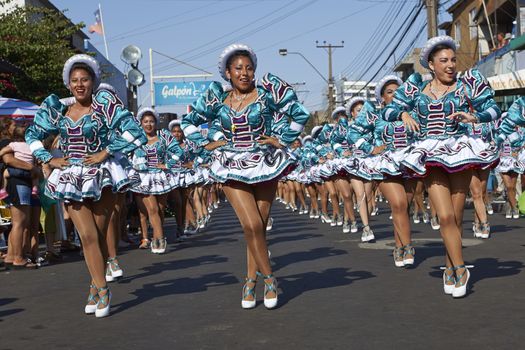 Female members of a Caporales dance group in ornate costumes performing at the annual Carnaval Andino con la Fuerza del Sol in Arica, Chile.