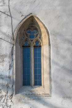 Original gothic window with a stone frame and a glass reflecting the sky. Church of Saint Cross in Devin, Bratislava, Slovakia.