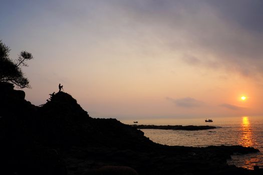Wonderful scene at Vietnam seaside in sunrise, yellow sun in sky, silhouette of people, boat on sea, abstract scene at Da Dia rapids in morning, amazing seascape for Phu Yen, Viet Nam