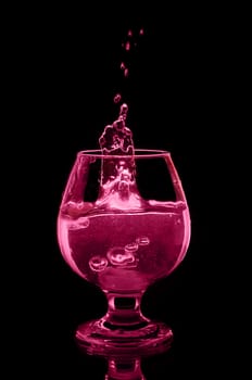 Pink drink with ice and splashes on black background