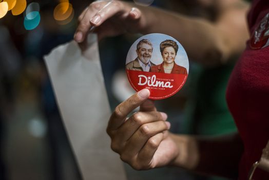BRAZIL, Curitiba: A pro-government protester holds a badge with the efffigy of President Dilma Rousseff and former President Luiz Inacio Lula da Silva during a demonstration in support of President Dilma Rousseff and former President Luiz Inacio Lula da Silva in Curitiba, Brazil, on March 18, 2016. Brazilian President Dilma Rousseff's supporters took to the streets Friday to fight back at attempts to oust her, as a flurry of court battles raged over her controversial cabinet appointment of predecessor Luiz Inacio Lula da Silva. 