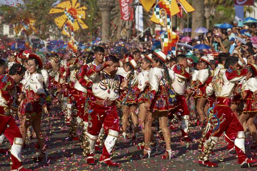 Caporales dance group in ornate red and white costumes performing at the annual Carnaval Andino con la Fuerza del Sol in Arica, Chile.