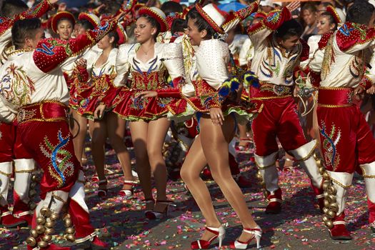 Caporales dance group in ornate red and white costumes performing at the annual Carnaval Andino con la Fuerza del Sol in Arica, Chile.