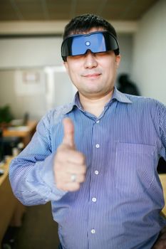 Man in glasses of virtual reality shows thumb up