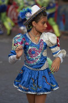 Female member of a Caporales dance group in ornate red and white costumes performing at the annual Carnaval Andino con la Fuerza del Sol in Arica, Chile.