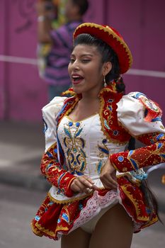 Caporales dancer in ornate red and white costume performing at the annual Carnaval Andino con la Fuerza del Sol in Arica, Chile.