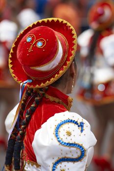 Caporales dancer in ornate red and white costume performing at the annual Carnaval Andino con la Fuerza del Sol in Arica, Chile.