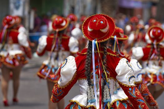 Caporales dancer in ornate red and white costume performing at the annual Carnaval Andino con la Fuerza del Sol in Arica, Chile.