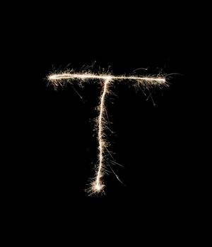 Letter T drew with spakrs on a black background.