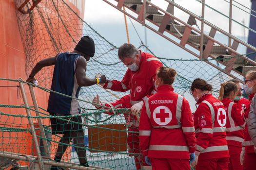 ITALY, Palermo: A medical worker helps a migrant off a ship in Palermo, Italy on March 19, 2016.712 migrants have arrived at the port of Palermo, on the military Norwegian ship Siem Pilot on March 19, 2016. Among them 598 men, 51 women, and 63 children came from 30 different nationalities including Nigeria, Senegal, Guinea, Sierra Leone and other Sub-saharan countries.