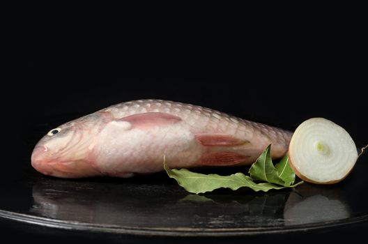 Raw fish on a black background and a wooden surface.