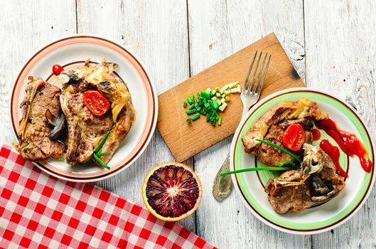 Two servings of roast beef,decorated with vegetables on decorated table.Top view