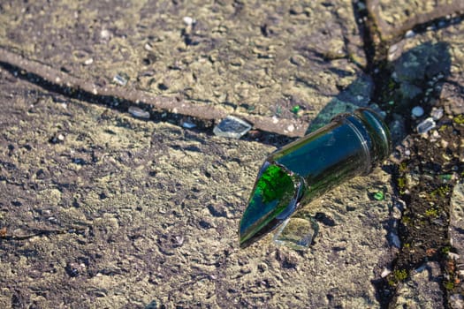 Broken bottle made of green glass as a symbol of vandalism and danger.