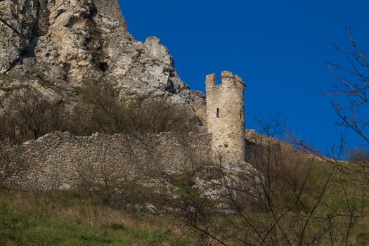 Ruins of the former famous fortress, Devin castle, Bratislava, Slovakia. Surrounding wall with a tower. Bright blue sky.