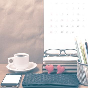 office desk : coffee with phone,wallet,calendar,color pencil box,stack of book,heart,eyeglasses on wood background vintage style