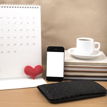 office desk : coffee with phone,wallet,calendar,heart,stack of book on wood background