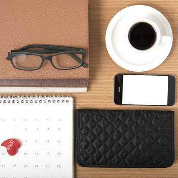 office desk : coffee with phone,stack of book,eyeglasses,wallet,calendar,heart on wood background