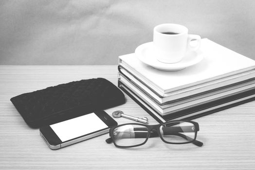 coffee and phone with stack of book,key,eyeglasses and wallet on wood background black and white color