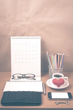 office desk : coffee with phone,wallet,calendar,heart,notepad,eyeglasses,color pencil box,key on wood background vintage style