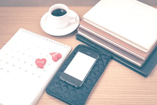 office desk : coffee with phone,wallet,calendar,heart,stack of book on wood background vintage style