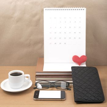 office desk : coffee with phone,stack of book,eyeglasses,wallet,calendar,heart on wood background