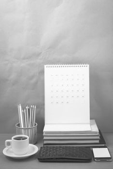 office desk : coffee with phone,wallet,calendar,color pencil box,stack of book on wood background black and white color