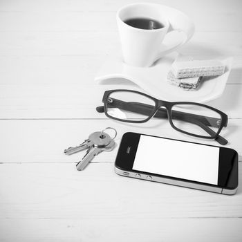 coffee cup with wafer,phone,key,eyeglasses on white wood background black and white color