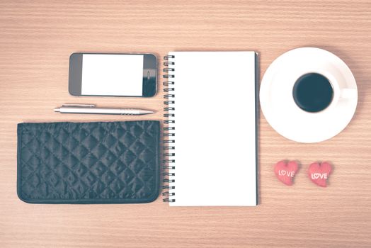 working table : coffee with phone,notepad,wallet and red heart on wood background vintage style
