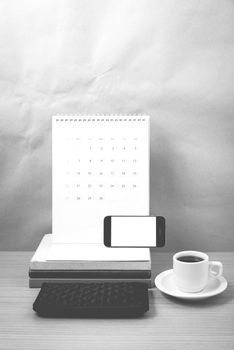 working table : coffee with phone,stack of book and wallet on wood background black and white color