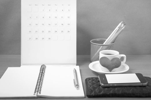 office desk : coffee with phone,wallet,calendar,heart,color pencil box,notepad,heart on wood background black and white color