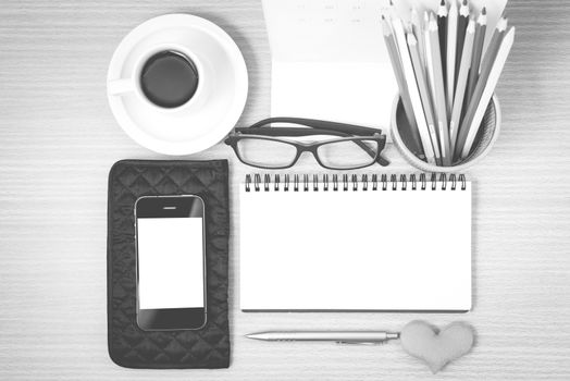 office desk : coffee with phone,wallet,calendar,color pencil box,notepad,heart on wood background black and white color