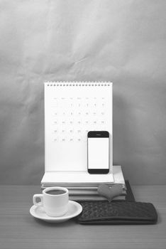 office desk : coffee with phone,wallet,calendar,heart,stack of book on wood background black and white color