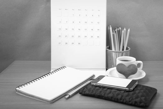 office desk : coffee with phone,wallet,calendar,heart,color pencil box,notepad,heart on wood background black and white color