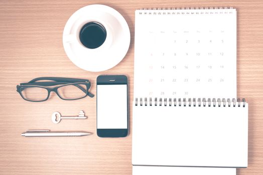 coffee and phone with key,eyeglasses,notepad,calendar on wood table background vintage style