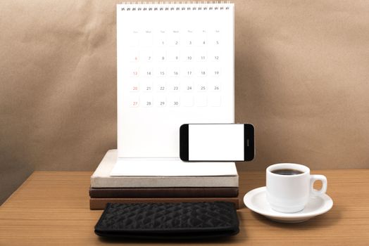 working table : coffee with phone,stack of book and wallet on wood background