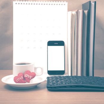 office desk : coffee with phone,wallet,calendar,heart,stack of book on wood background vintage style