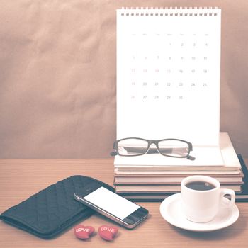 office desk : coffee with phone,wallet,calendar,heart,stack of book,eyeglasses on wood background vintage style