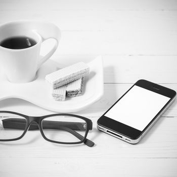coffee cup with wafer,phone,eyeglasses on white wood background black and white color