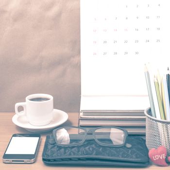 office desk : coffee with phone,wallet,calendar,color pencil box,stack of book,heart,eyeglasses on wood background vintage style