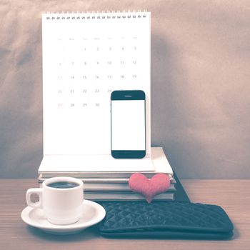 office desk : coffee with phone,wallet,calendar,heart,stack of book on wood background vintage style