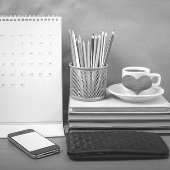 office desk : coffee with phone,wallet,calendar,heart,color pencil box,stack of book,heart on wood background black and white color