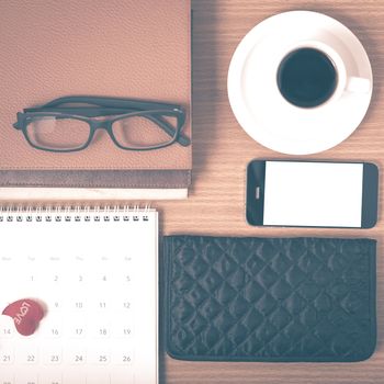 office desk : coffee with phone,stack of book,eyeglasses,wallet,calendar,heart on wood background vintage style
