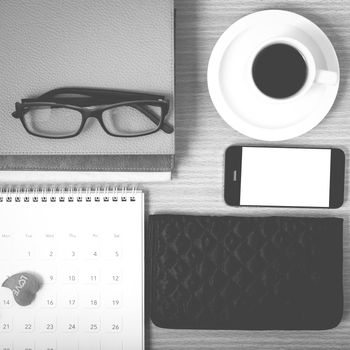 office desk : coffee with phone,stack of book,eyeglasses,wallet,calendar,heart on wood background black and white color