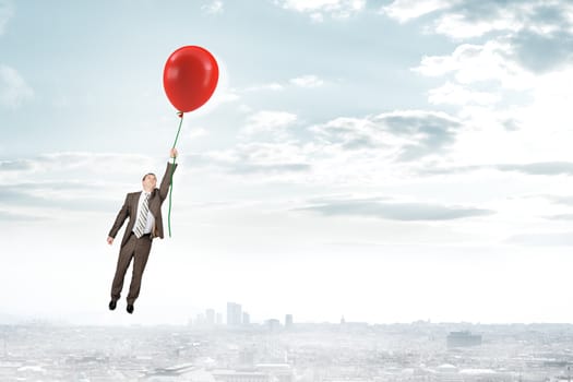 Businessman holding red balloon and flying above city, business concept
