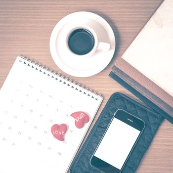 office desk : coffee with phone,wallet,calendar,heart,stack of book on wood background vintage style