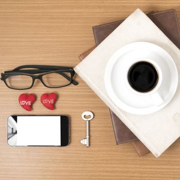 office desk : coffee and phone with key,eyeglasses,stack of book,heart on wood background