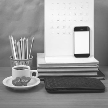 office desk : coffee with phone,wallet,calendar,heart,color pencil box,stack of book,heart on wood background black and white color