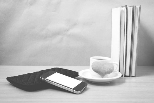 working table : coffee with phone,stack of book,wallet and heart on wood background black and white color